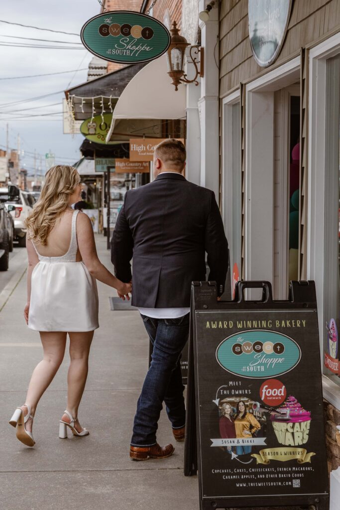 A bride and groom walk through downtown Blue Ridge holding hands on their way to pick up their wedding cake.