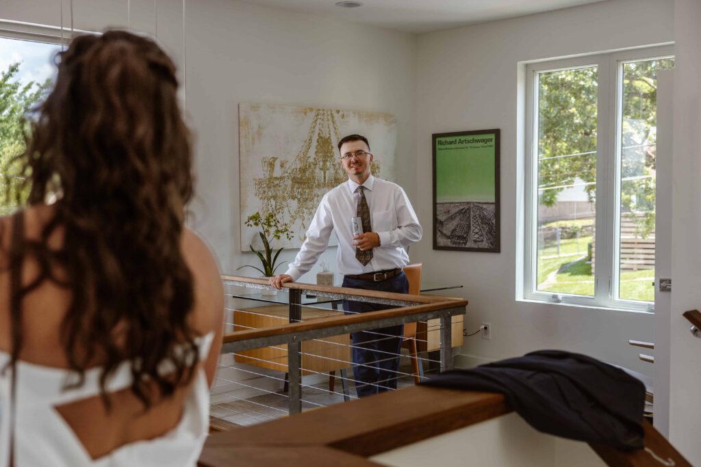 A groom stands looking and smiling at his bride as he see's her for the first time on their elopement day.