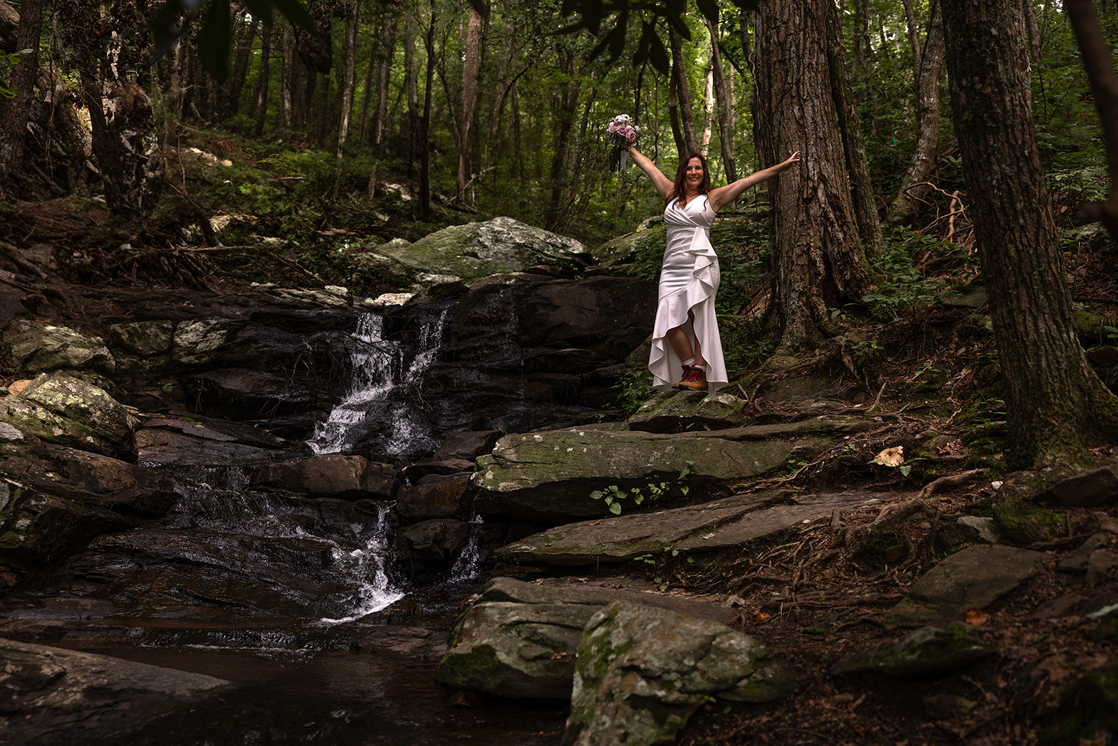 bride poses on top of a waterfall during her elopement photo session!