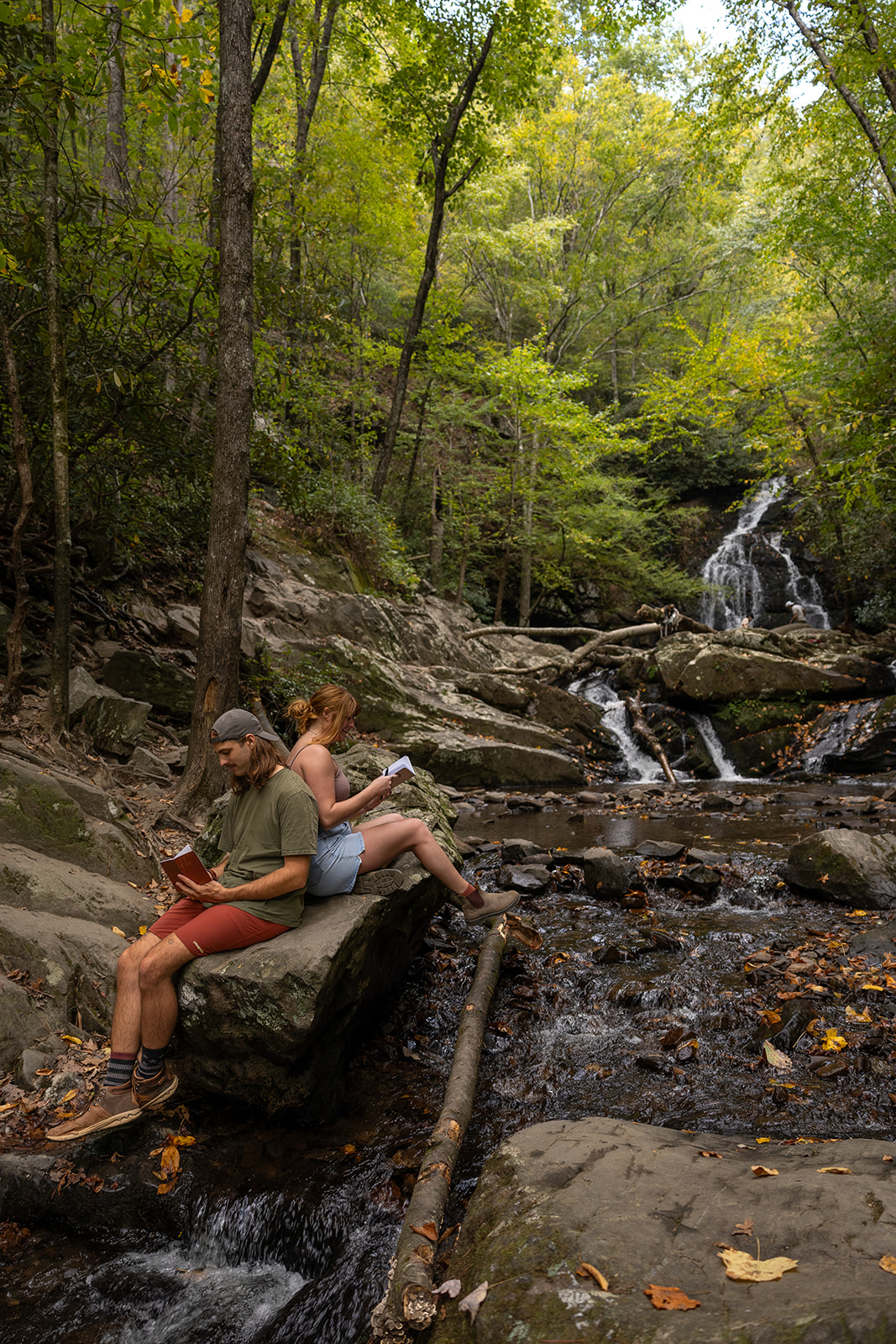 bride and groom sit on a rock in the stream as the water meananders around them 