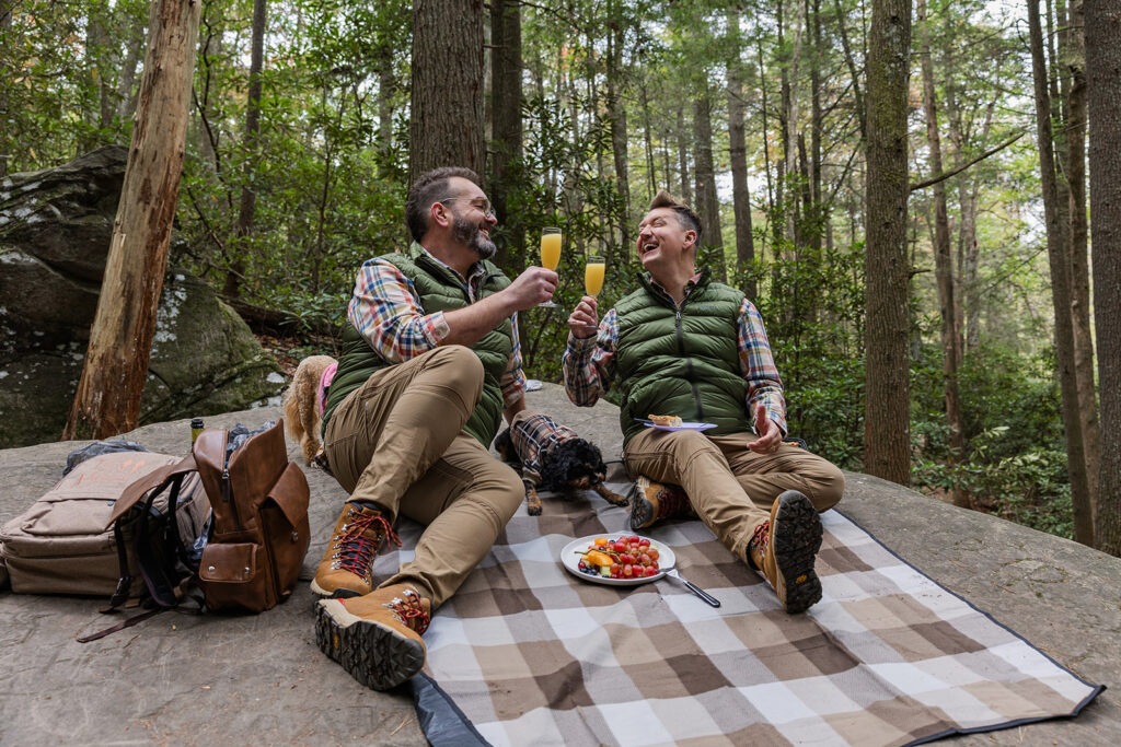 Two grooms share a toast after reading their vows in front of a waterfall. 