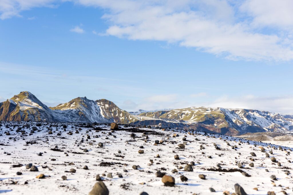 A snowy ground covered in rocks with vast mountains in the background. This would make for the perfect unique backdrop for an elopement in Iceland