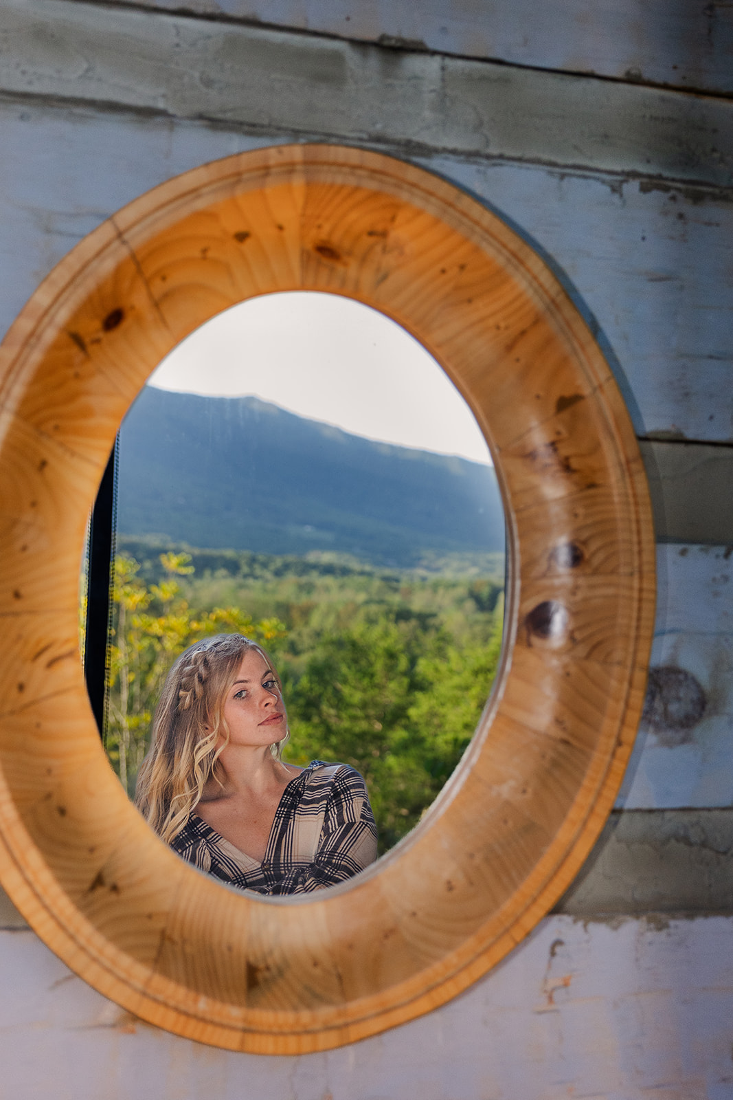 bride poses in a mirror with the mountains in the background