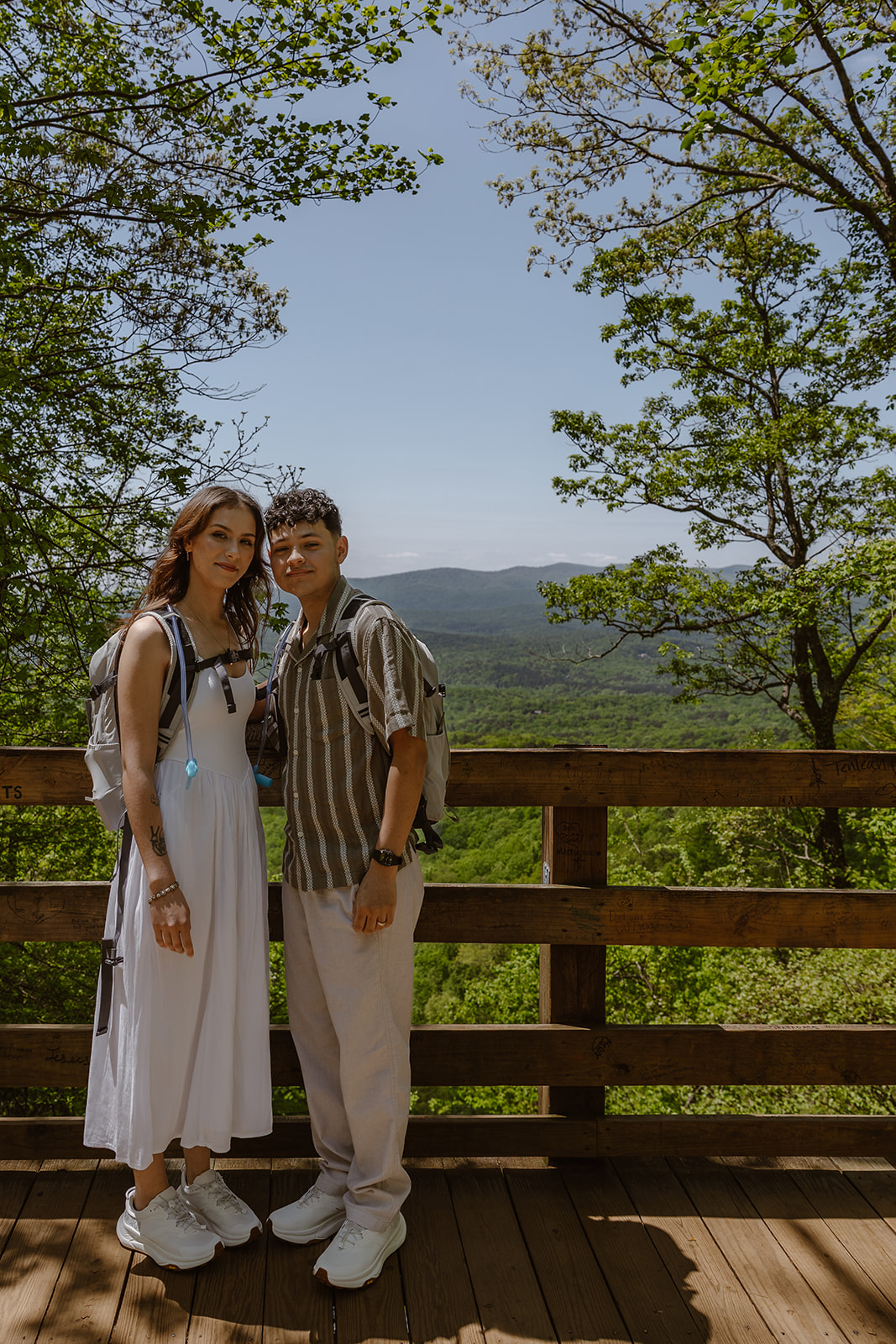 couple pose for a photo with the mountains in the background 