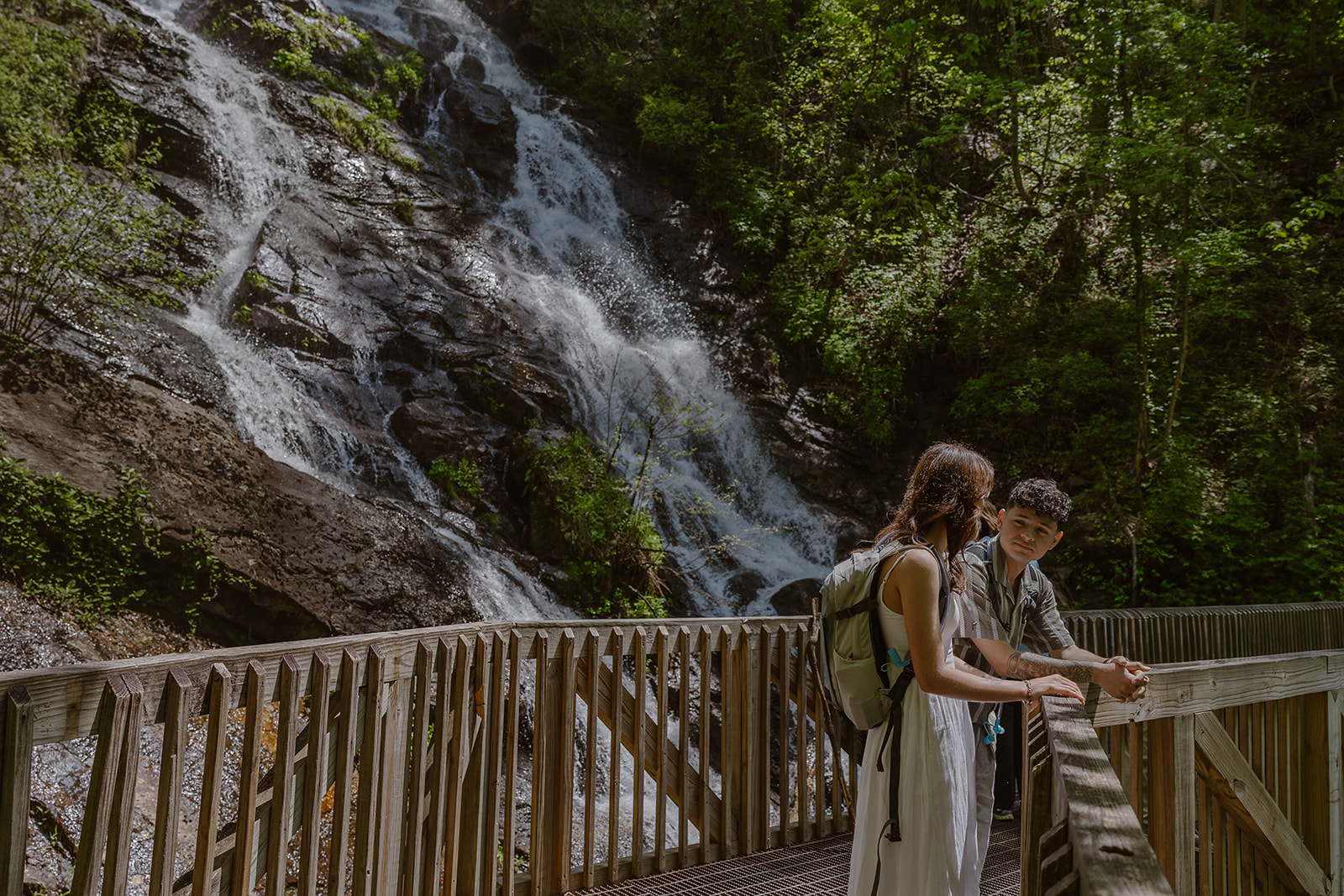 couple pose for a photo with a waterfall in the background 