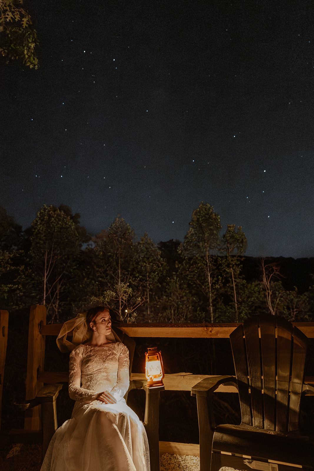 bride sits beside a lantern with the stars shining over her head