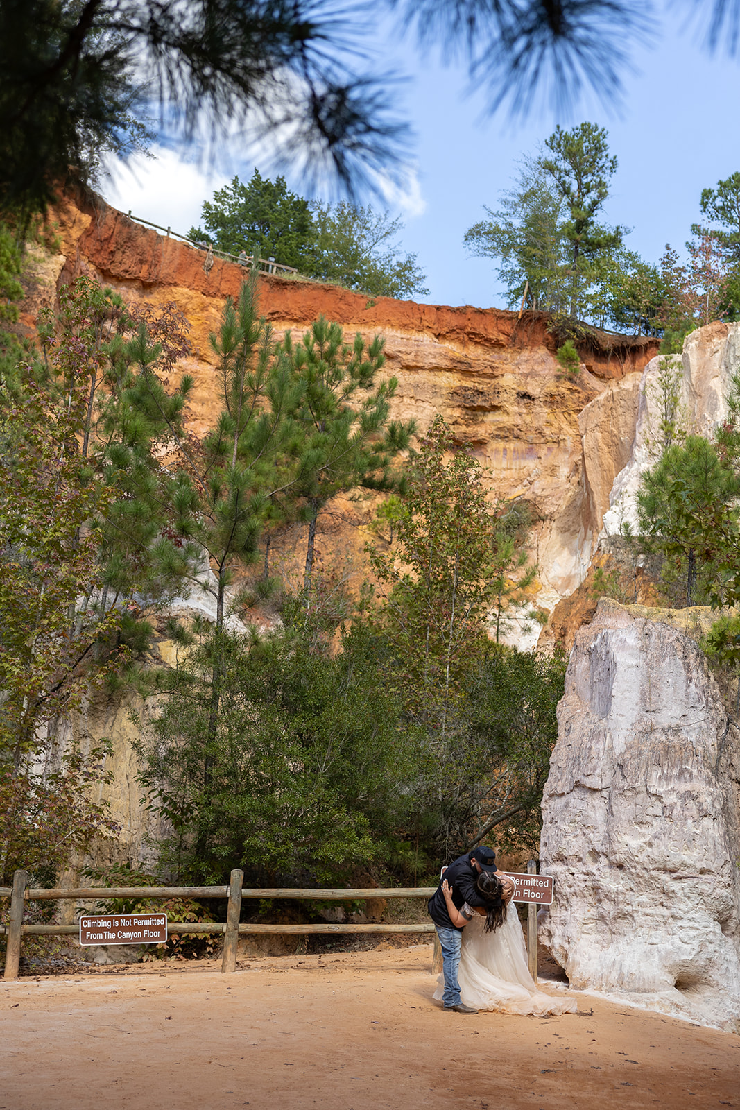 bride and groom walk along the canyon floor and stop for a kiss