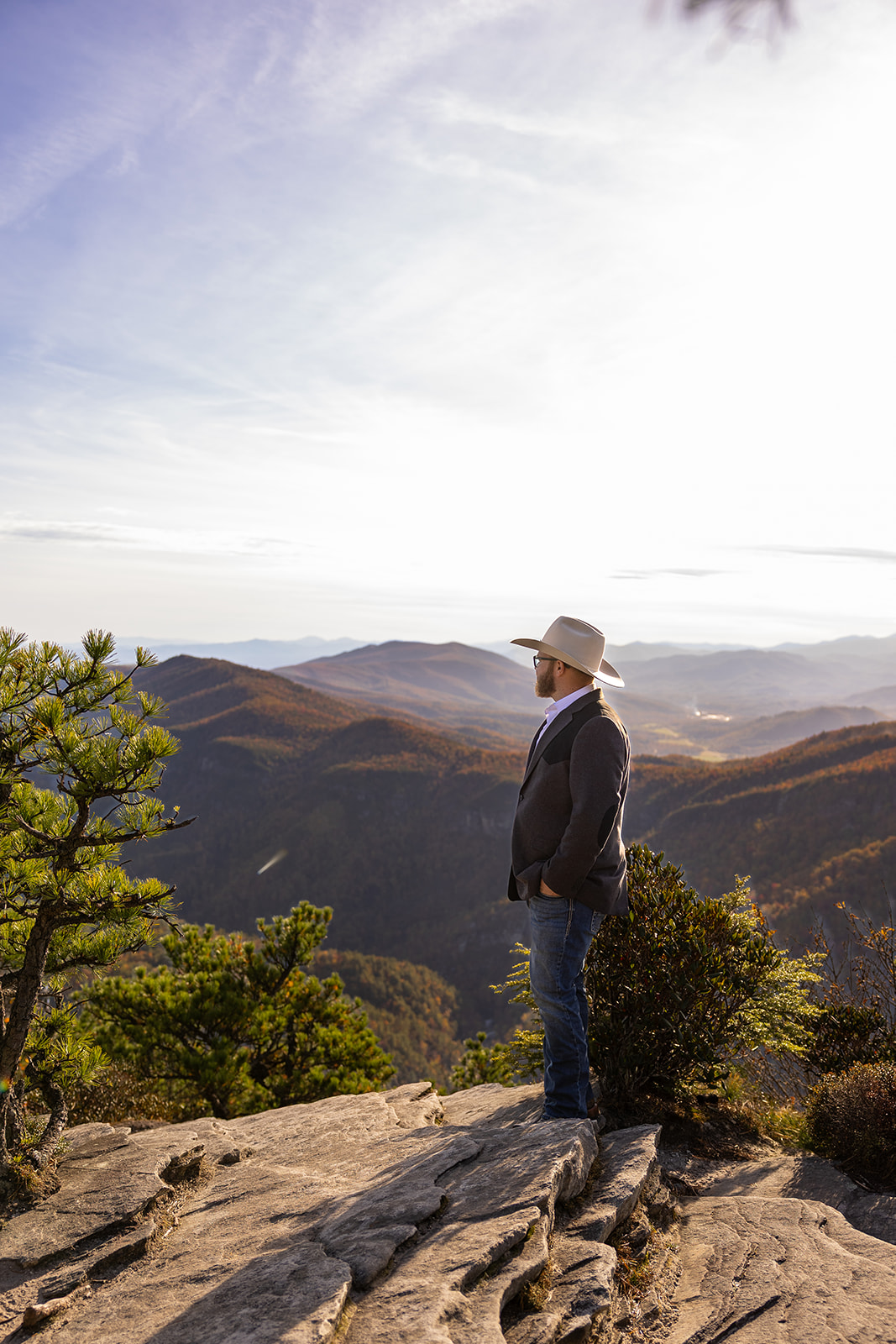 groom poses for a photo with the blue ridge mountains in the background