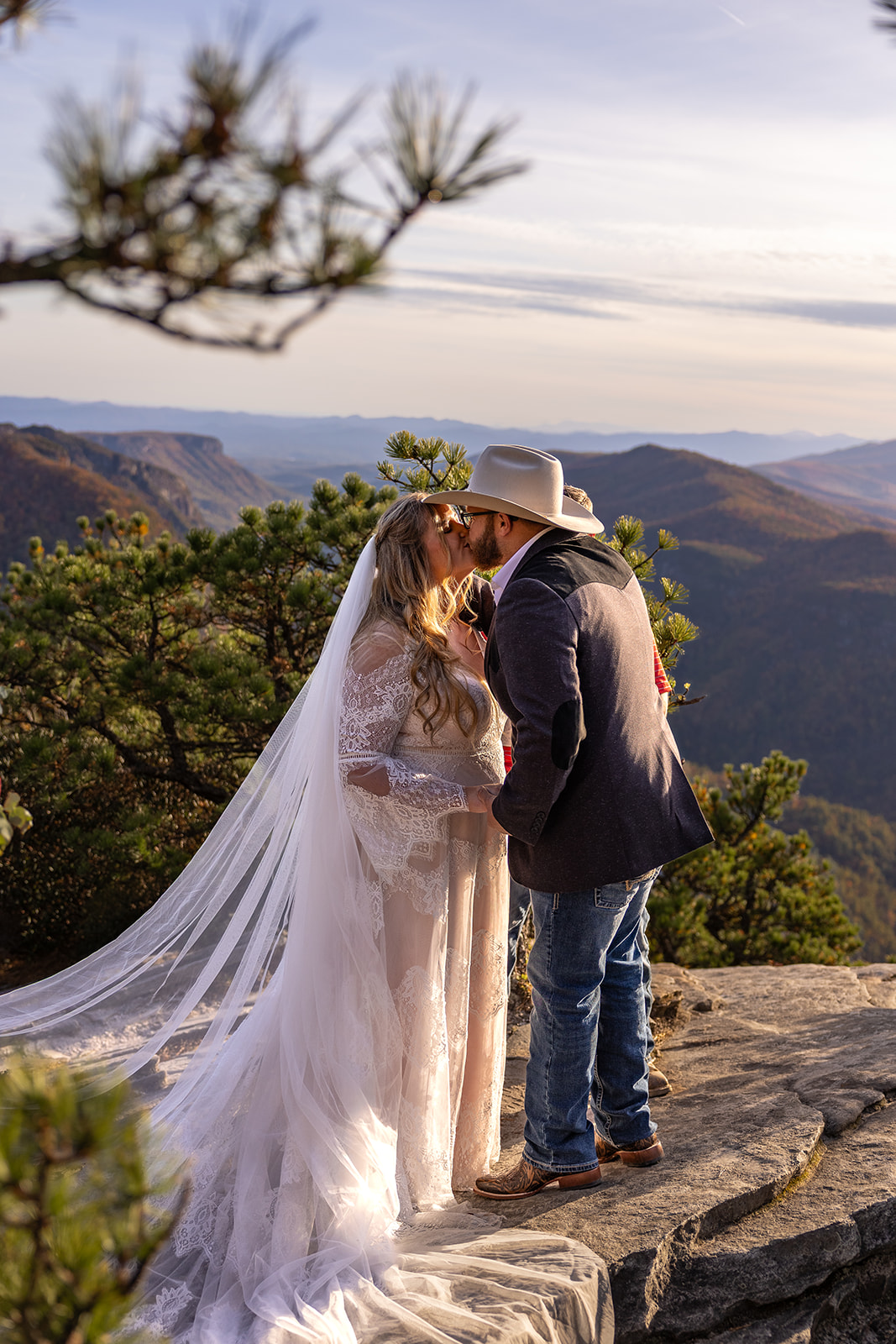bride and groom share a kiss on the edge of the cliff after their mountain elopement