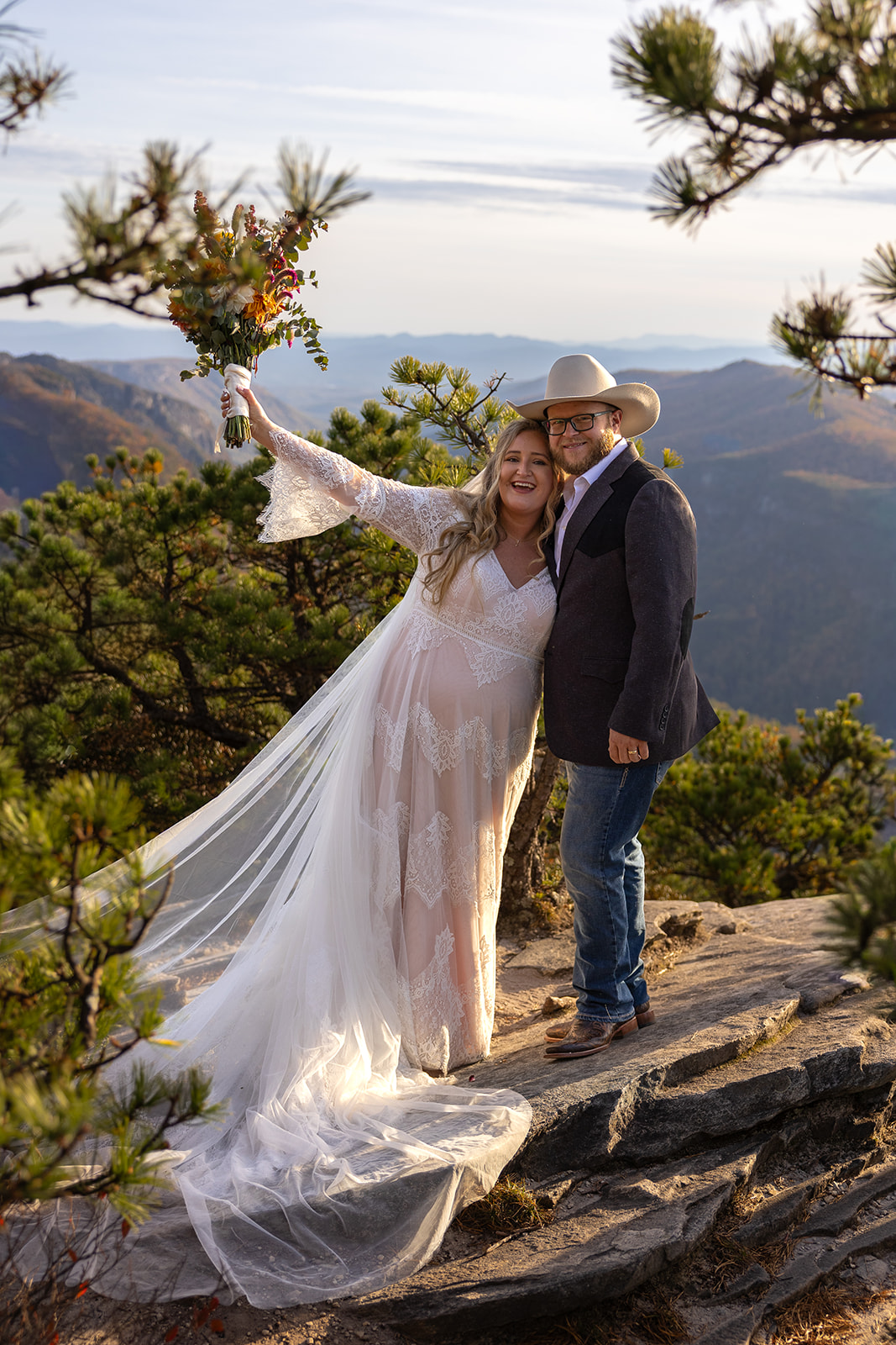 bride and groom pose for a photo with the mountains in the background