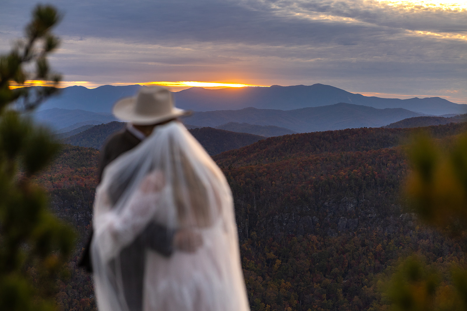 couple look out on the stunning sunset over the mountains after their elopement in the mountains