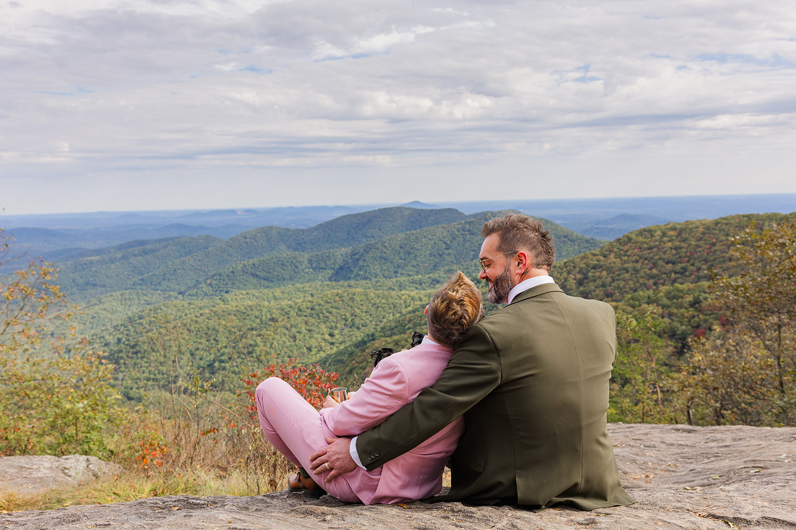 couple sit on the cliff and look out at the mountains at the end of their elopement day in the mountains