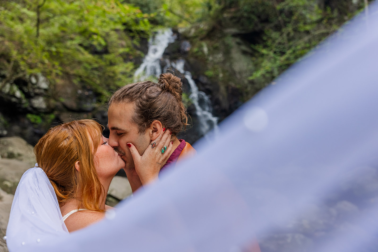 bride and groom share a kiss with the veil in the frame