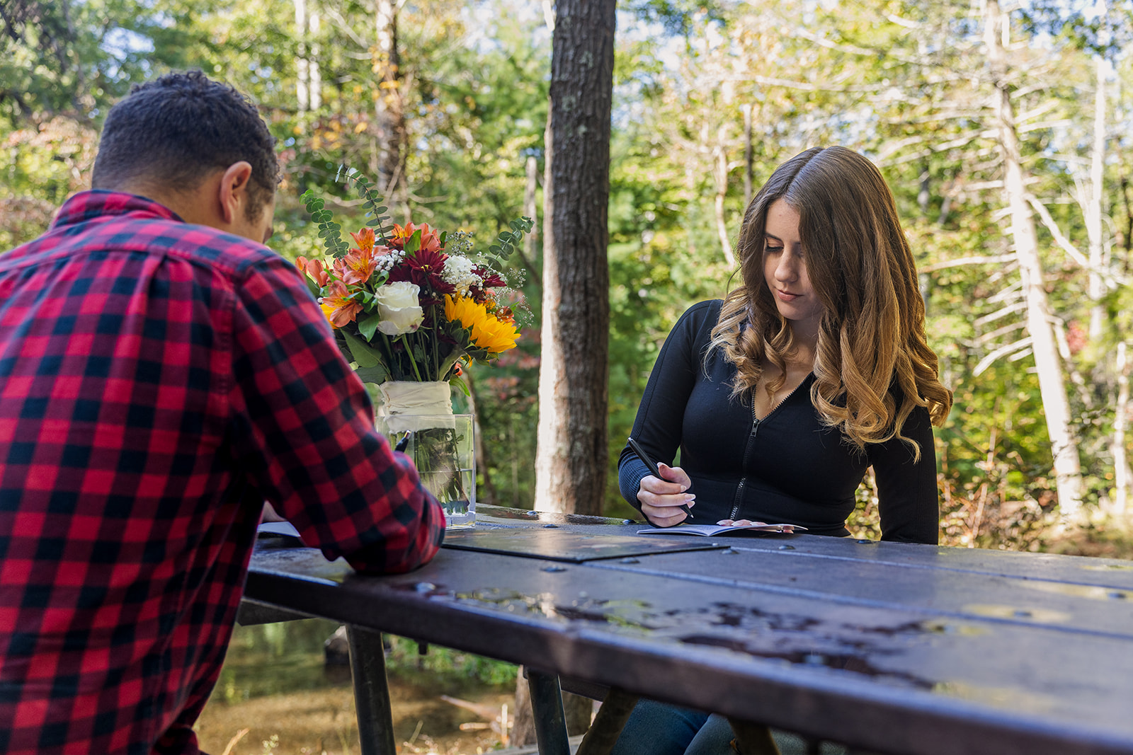 couple write their private vows while sitting at the picnic table together