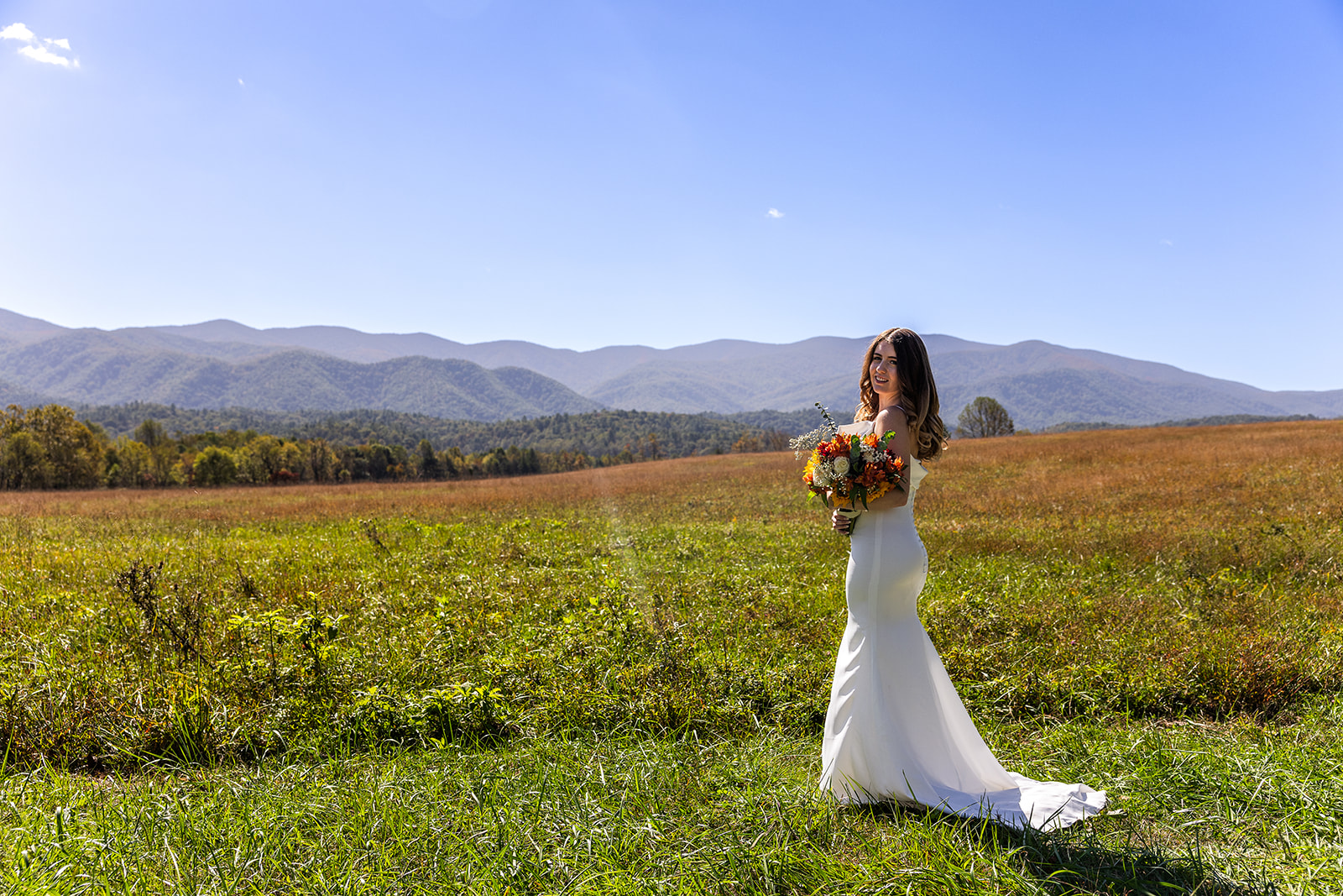 bride poses with her bouquet with te mountains in the background